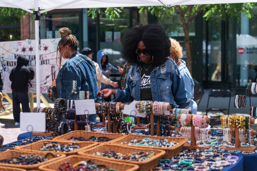 Woman in denim outfit shops bracelet collection at the Maxwell Street Market in Chicago.